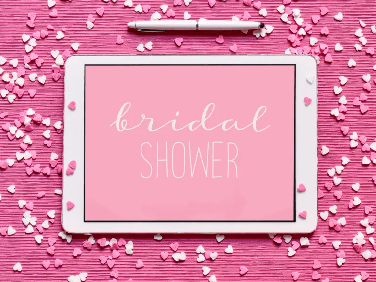 A pink tablet with Bridal Shower written on it and a pen above it, with hearts scattered around it. Representative of unique bridal shower games.