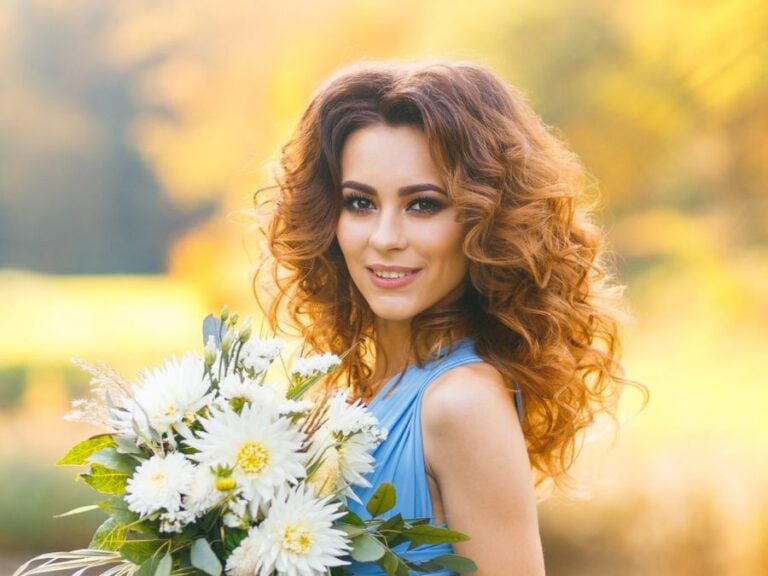 Demonstrating bridesmaid hairstyles for curly hair, holding a bouquet